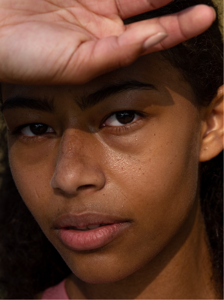 A women with the back of her hand on her forehead looking at the camera.