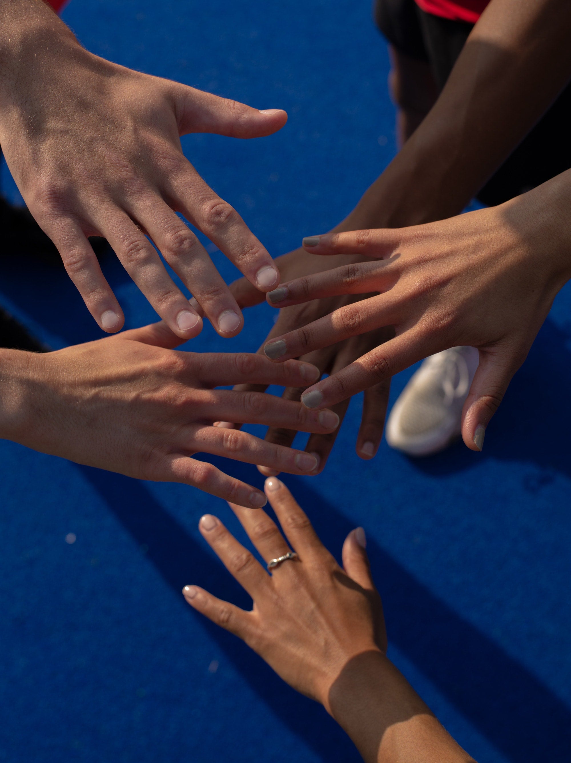 5 people's hands reaching in toward each other.